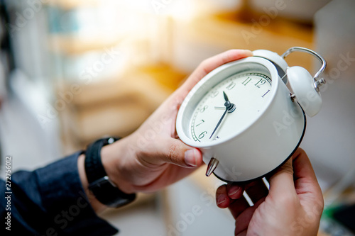 Male hand adjusting or changing the time on white clock. Time management concept.