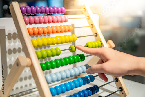 Male hand calculating with beads on wooden rainbow abacus for number calculation. Mathematics learning concept