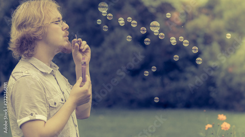 man blowing soap bubbles, having fun
