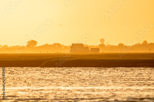 Golden light shining on a small bay house on the water at sunset. Long Island New York. 
