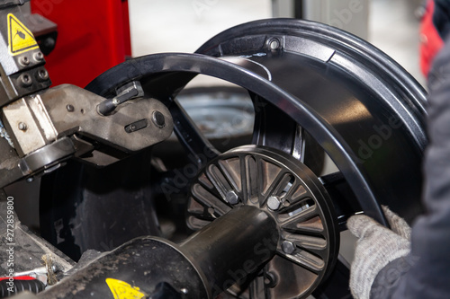 The process of repairing an automobile wheel using a special press on a machine for straightening disks for vehicles after damage in a pit on the road in the workshop. Auto service industry.