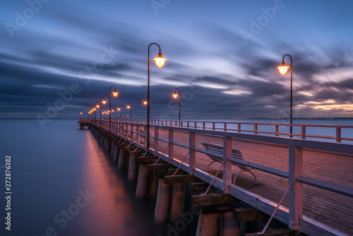 Illuminated wooden pier in Gdynia Orlowo. Early morning on the Baltic Sea. Poland, Europe.