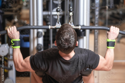 Man training dorsal muscles by taking handles and bringing them down. Strength exercising concept .