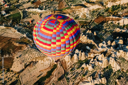 Goreme, Turkey - June 14, 2019: Travelers and tourists flying over mountains at sunset in a colorful aerostat balloon in Goreme, the Turkish cappadocia.