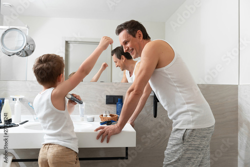 Little son using deodorant in the bathroom