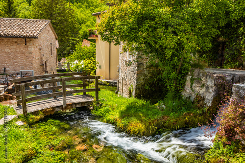 The small village of Rasiglia, crossed by many streams and waterfalls, fed by the Menotre river. A sluice regulates the flow of water. A wooden bridge. Old brick houses. Foligno, Umbria.