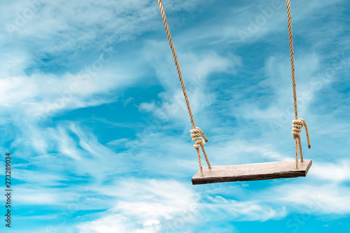 Wooden swing with pastel blue sky and cloud background