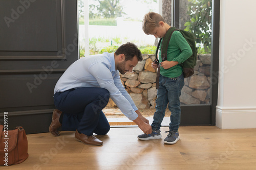 Father tying his sons shoelaces in a comfortable home