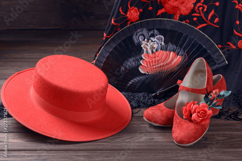 Beautiful and bright accessories for flamenco dance on a wooden background. Shawl, hat, fan, shoes, castanets and a flower for the hair.