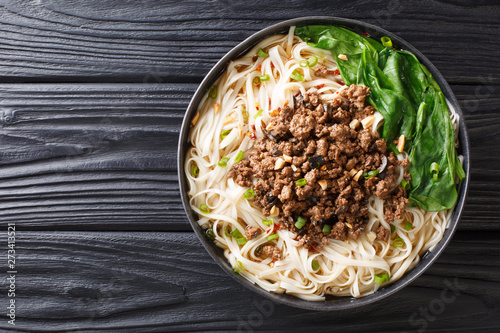 recipe for dan dan noodles with minced meat and greens closeup in a plate. horizontal top view