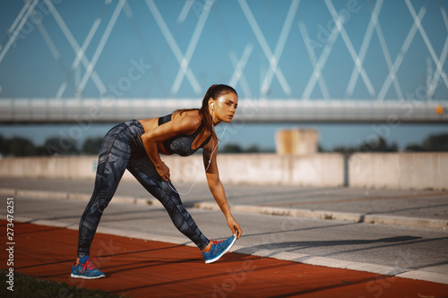 Young woman warming up and stretching legs before jogging