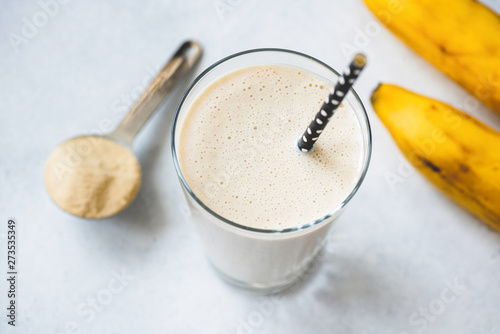 Vegan protein banana shake or smoothie in glass. Top view, selective focus