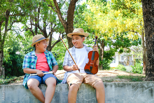 Happy, two boys smiling and laughing, playing music, violins and flutes at the backyard