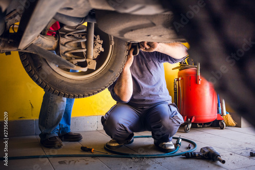 Photo of car mechanics fixing the car. Inside the car shop.