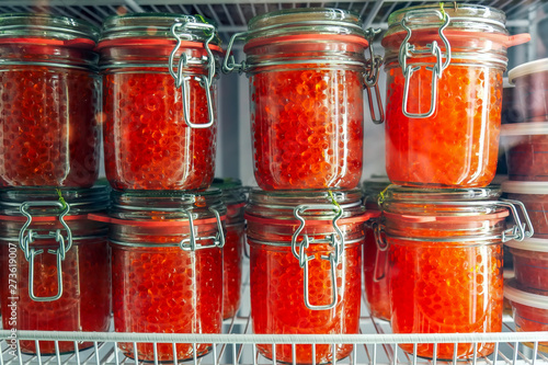 Jars with delicious red caviar in the fridge. Delicious expensive snack