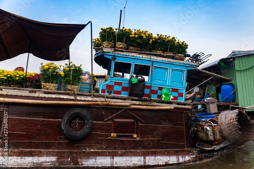 Close-up of a brown and blue boat or sampan carrying yellow and red flowers for Tet New Year Celebration, Mekong Delta, Vietnam.