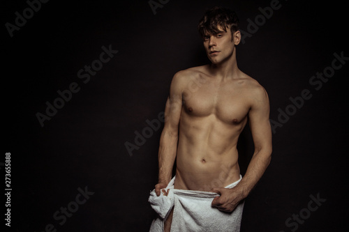 Strong stripped muscle male model with white towel on black isolated font background