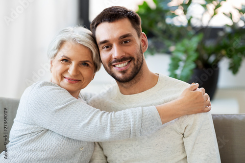 family, generation and people concept - happy smiling senior mother with adult son hugging at home