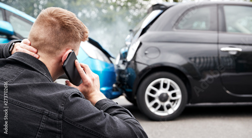 Young Male Motorist Involved In Car Accident Calling Insurance Company Or Recovery Service