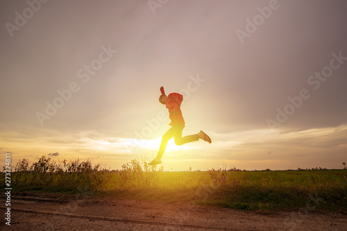 Young man jump over paddy field meadow with sunset scenic, freedom, escape concept, copy space.