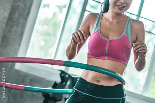 unrecognized Female in pink sportwear is working out with Hula hoop in fitness gym for healthy lifestyle concept