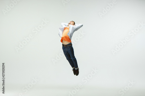 Happy young man working at office, jumping and dancing in casual clothes or suit isolated on white studio background. Business, start-up, working open-space, ballet or professional occupation concept.