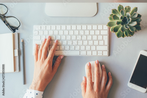 Top view of the workplace, elegant female hands on the keyboard of a personal computer in the office or at home, suitable for both freelancing and office content. Business lady prints 