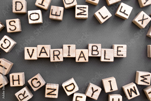 the word variable wooden cubes with burnt letters, variable life, gray background top view, scattered cubes around random letters