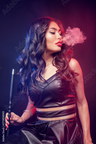 Young, beautiful woman in the night club or bar smoke a hookah or shisha