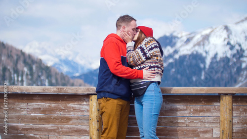 A young couple tourists standing on a background of mountains and kiss