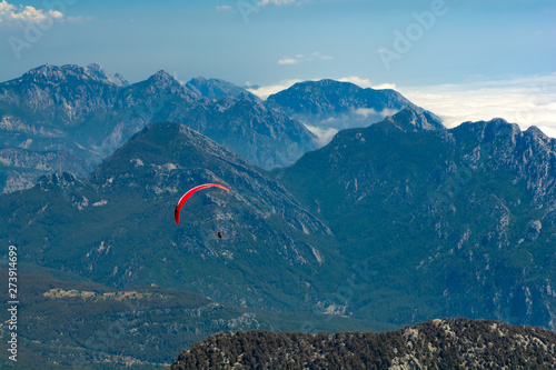Paragliding flying in the sky over mountains and sea. Aerial view from Tahtali mountain, Turkey. Extreme sport or travel concept
