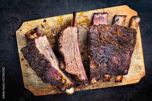 Barbecue chuck beef ribs with hot rub as top view sliced on a wooden cutting board