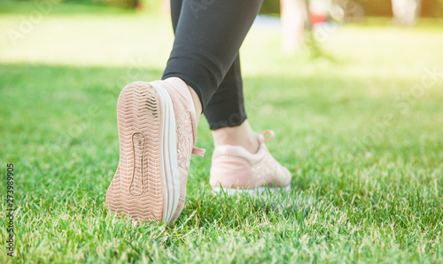 Running shoes girl on grass in summer park.