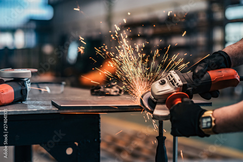 Grinding metal part at factory workshop, close-up.