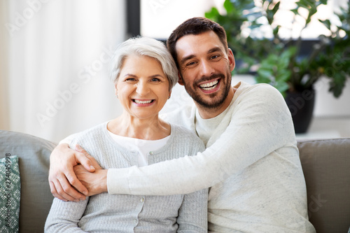 family, generation and people concept - happy smiling senior mother with adult son hugging at home