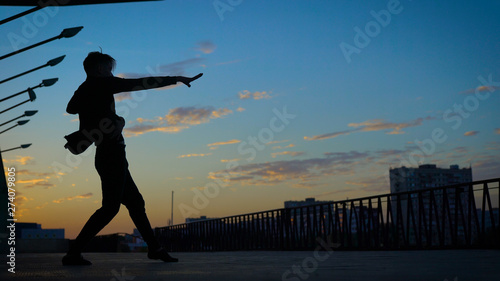 A man is dancing against a background of the evening sky. Dance in the style of Contemporary.