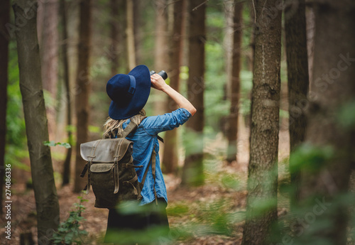 Young woman with binocular and backpack in a forest