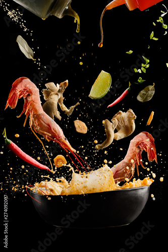 flying soup tom yam with shrimp and spices. Concept of food preparation in low gravity mode, food levitation. Separated on black background. High resolution image