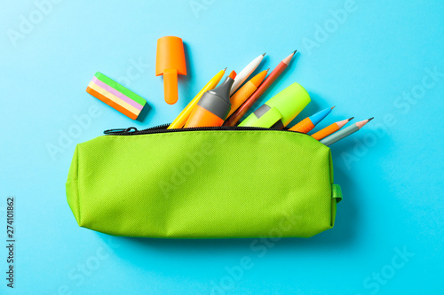 Pencil case with school supplies on blue background, space for text