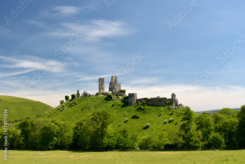 The historic landmark outline of Corfe Castle above the fields in Dorset