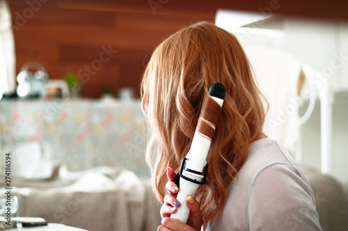 ヘアアイロンで髪を巻く女性