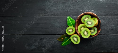 Fresh kiwi and green leaves on the table. Rustic style. Fruits. Top view. Free space for text.