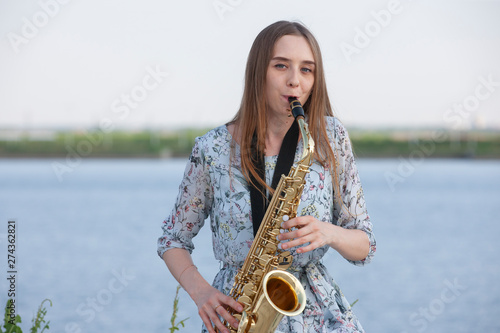 Young woman with saxophone with nature background