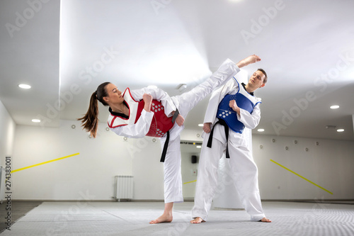 Young woman training martial art of taekwondo with her coach