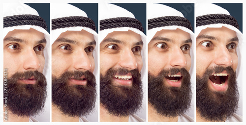 Half-length portrait of arabian saudi businessman on dark blue studio background. Young male model proceed of getting astonished. Concept of business, finance, facial expression, human emotions.