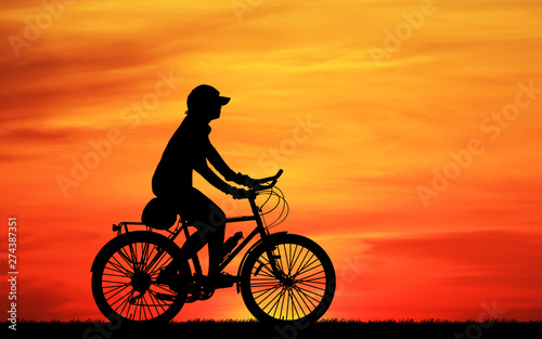 Silhouette man and bike relaxing on blurry sunrise sky background.