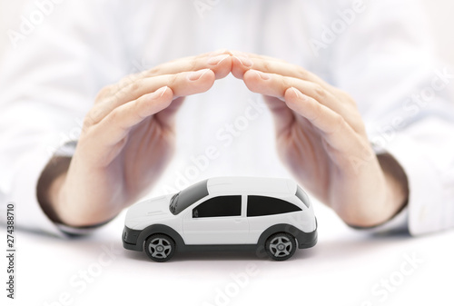 Car insurance concept with white car toy covered by hands 