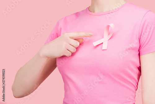partial view of woman in pink t-shirt pointing with finger at silk breast cancer sing isolated on pink