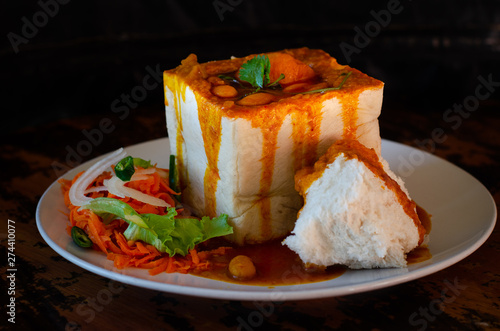 A Durban Bunny Chow - or, here, a vegerarian quarter bean bunny - served with sambals. This is an iconic Durban meal consisting of a section of a loaf of bread hollowed out and filled with beans