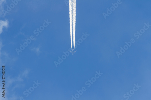 Avion a reaccion volando en el cielo azul. Dejando rastro estela o chorro de vapor de agua, visto desde abajo en plano nadir